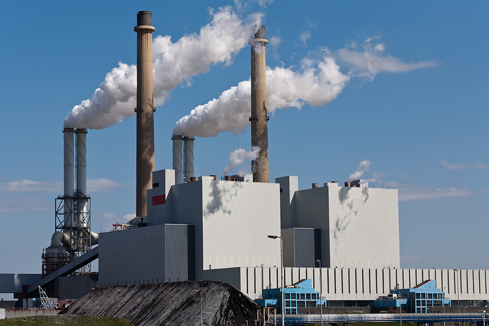 A skyline image of a factory releasing steam into the sky